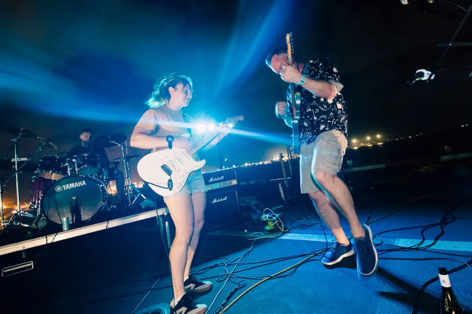 Two guitarists playing under blue stage lights